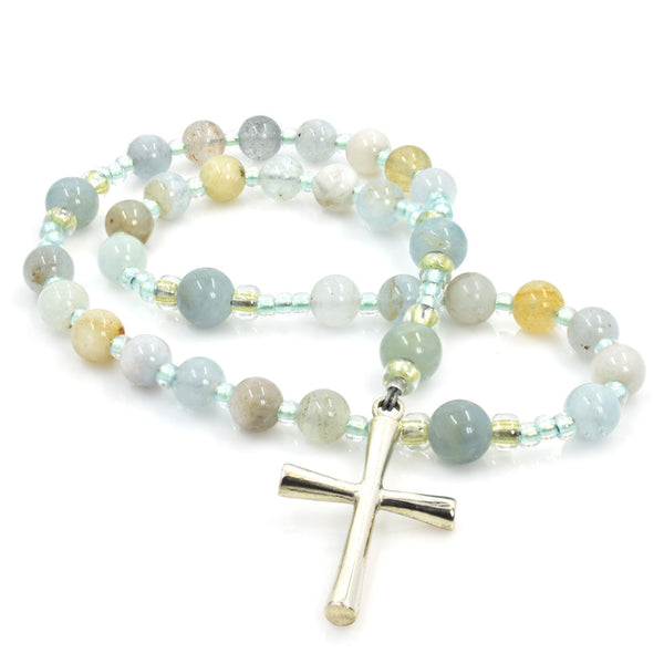 A string of round aquamarine beads, blue and yellow, with a silver Latin cross pendant at the center.