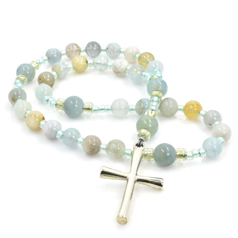 A string of round aquamarine beads, blue and yellow, with a silver Latin cross pendant at the center.